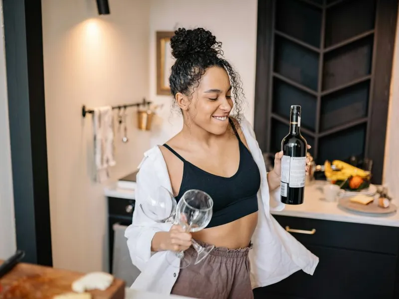 Femeie dansând, în timp ce ţine în mână o sticlă de vin - Foto: Pexels/Yan Krukau