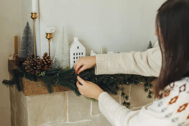 Femeie care pune un aranjament de Crăciun - Foto: Freepik (Imagine cu rol ilustrativ)