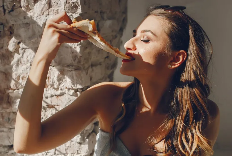 T&acirc;nără femeie m&acirc;nc&acirc;nd pizza - Foto: Magnific/prostooleh
