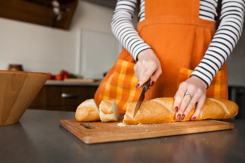 Persoană care taie o p&acirc;ine - Foto: Freepik (Imagine cu rol ilustrativ)