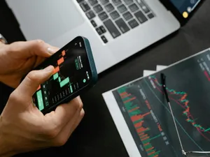 Persoană făcând calcule pe Bursă, pe telefonul său - Foto: Pexels/Tima Miroshnichenko
