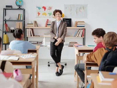 Profesoară stând în faţa clasei - Foto: Pexels/Max Fischer