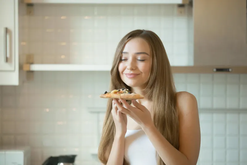 Femeie care măn&acirc;ncă pizza - Foto: Magnific.com (Imagine cu rol ilustrativ)