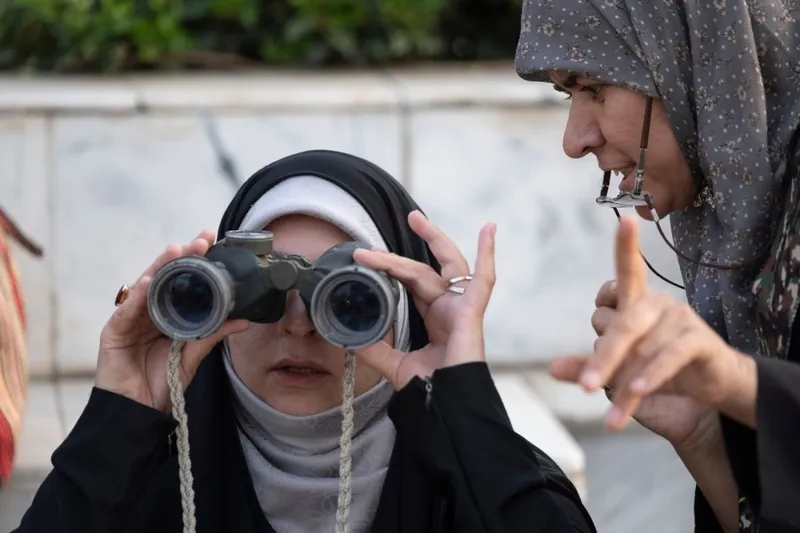 O femeie neidentificată o &icirc;nvaţă cum să folosească binoclul pe o membră a forțelor iraniene de sacrificiu volutar, l&acirc;ngă Teheran - Foto: Profimedia Images