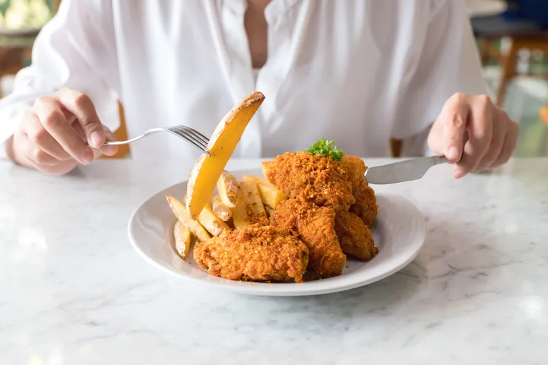 Persoană care mănâncă șnițele cu cartofi - Foto: Freepik (rol ilustrativ)