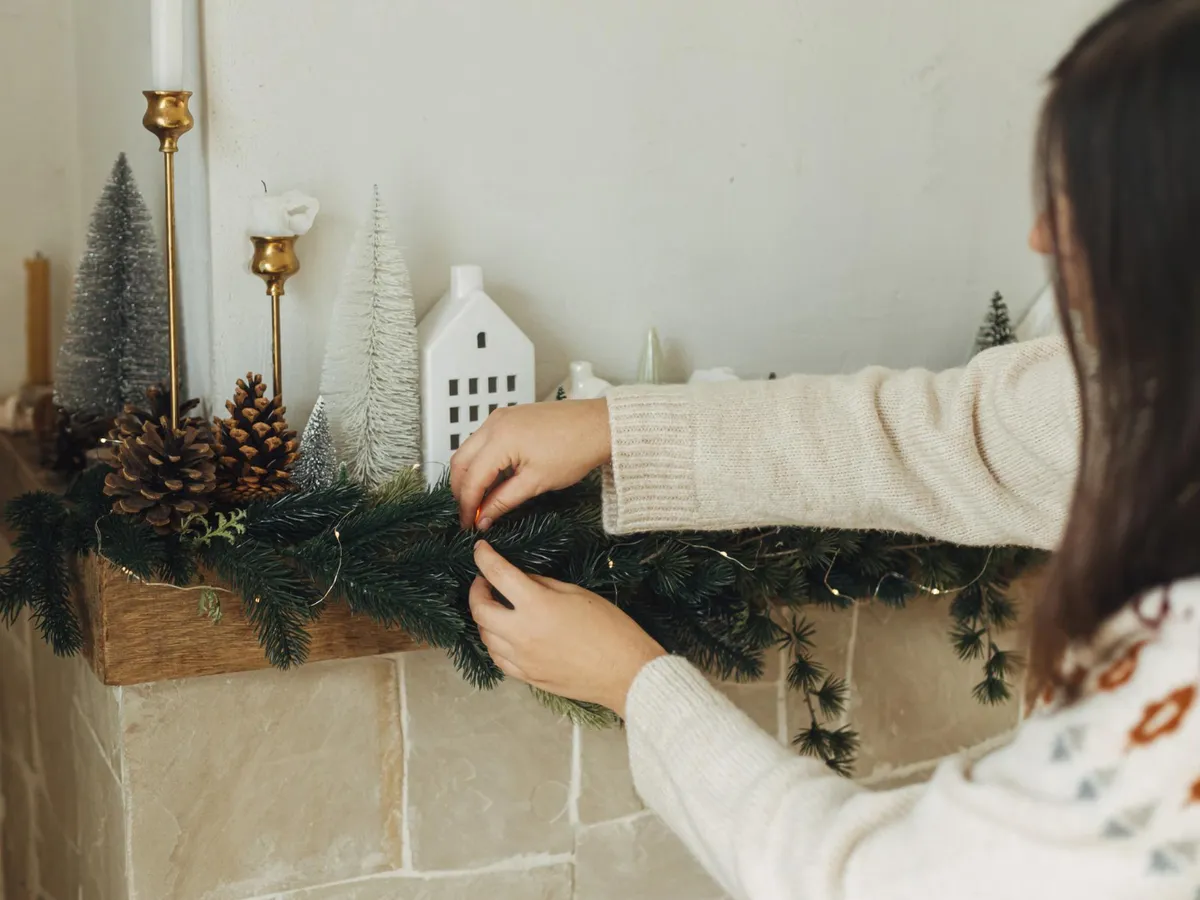 Femeie care pune un aranjament de Crăciun - Foto: Freepik (Imagine cu rol ilustrativ)