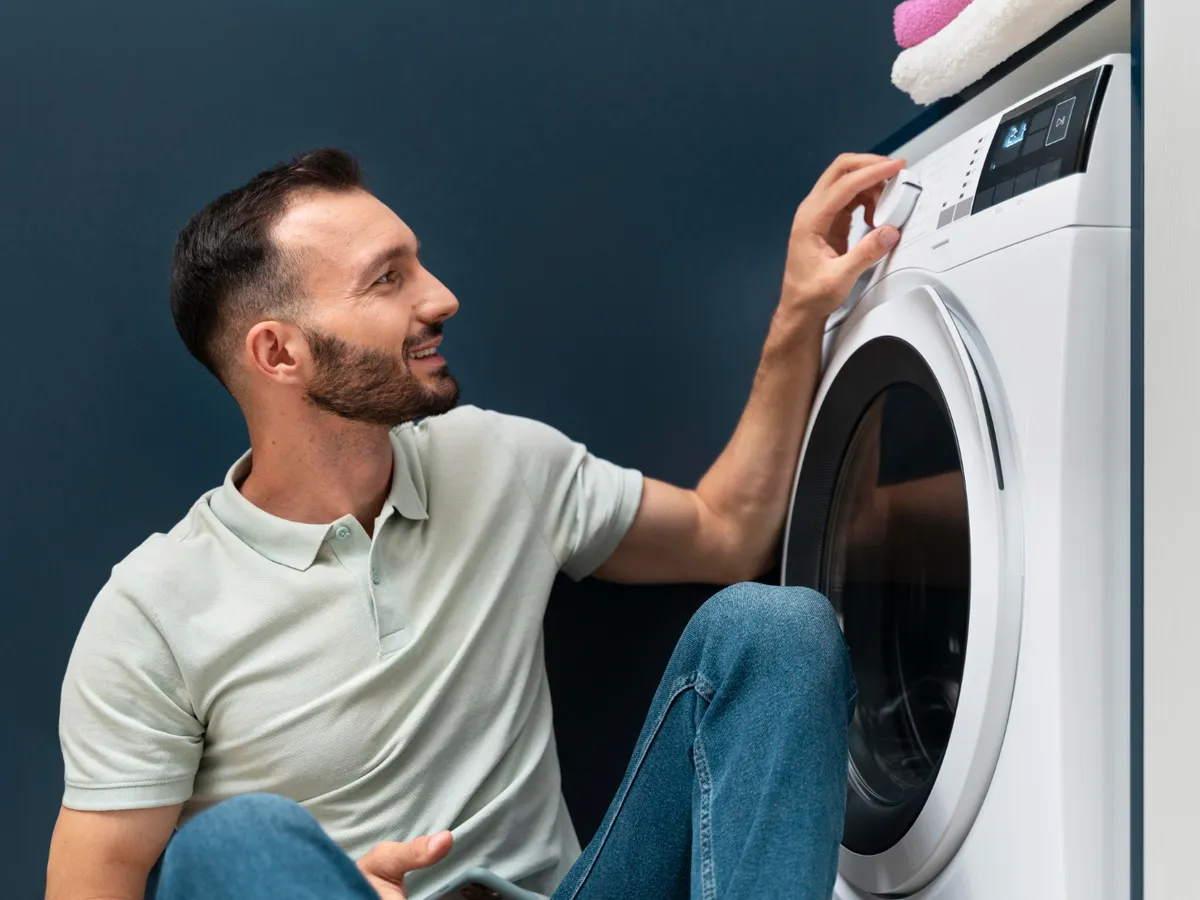 Bărbat care așteaptă ca mașina de spălat să termine programul - Foto: Magnific.com (Imagine cu rol ilustrativ)