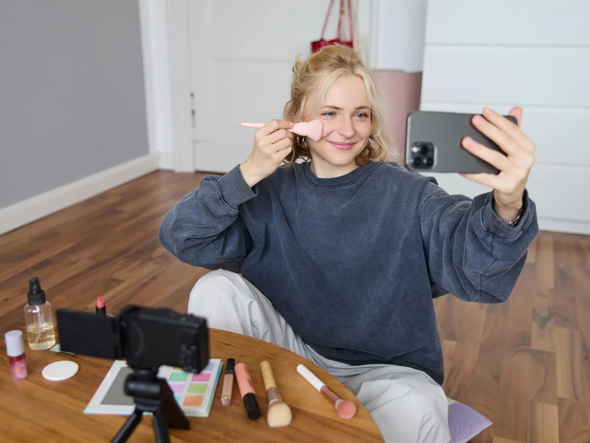 Tânără influencer transmițând în direct o ședință de machiaj - Foto: Freepik (cu rol ilustrativ)