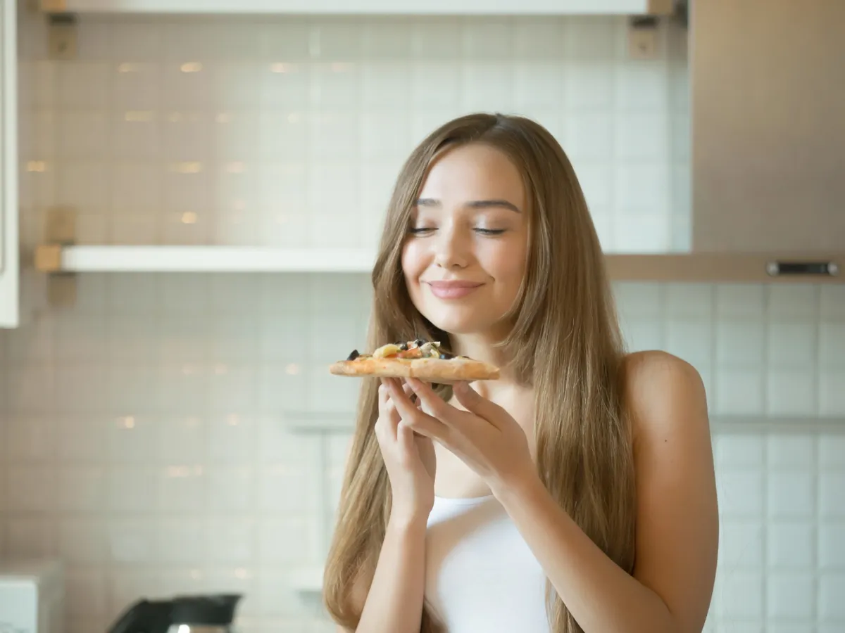 Femeie care mănâncă pizza - Foto: Magnific.com (Imagine cu rol ilustrativ)