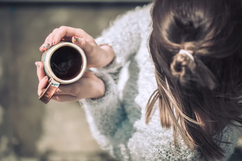 Femeie care ține în mână o ceașcă de cafea fierbinte - Foto: Freepik (rol ilustrativ)