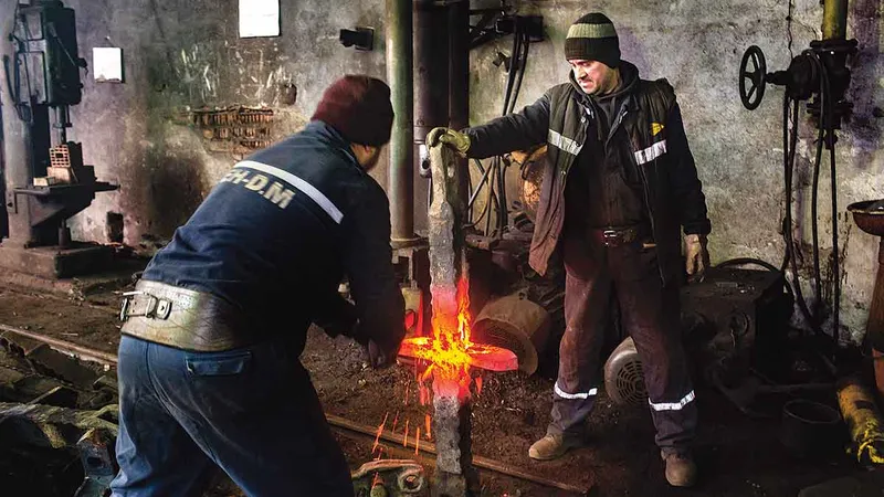 Gelu Sărăcuțu (dreapta) și colegul său care lucrează la îndreptarea stâlpilor de sprijin îndoiți sub presiune, la mina Vulcan