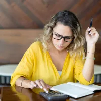 Femeie concentrată făcând calcule complicate - Foto: Freepik/katemangostar