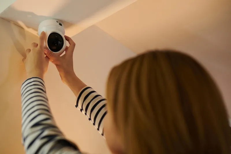 Femeie instal&acirc;nd o cameră de securitate - Foto: Magnific.com (Imagine cu rol ilustrativ)