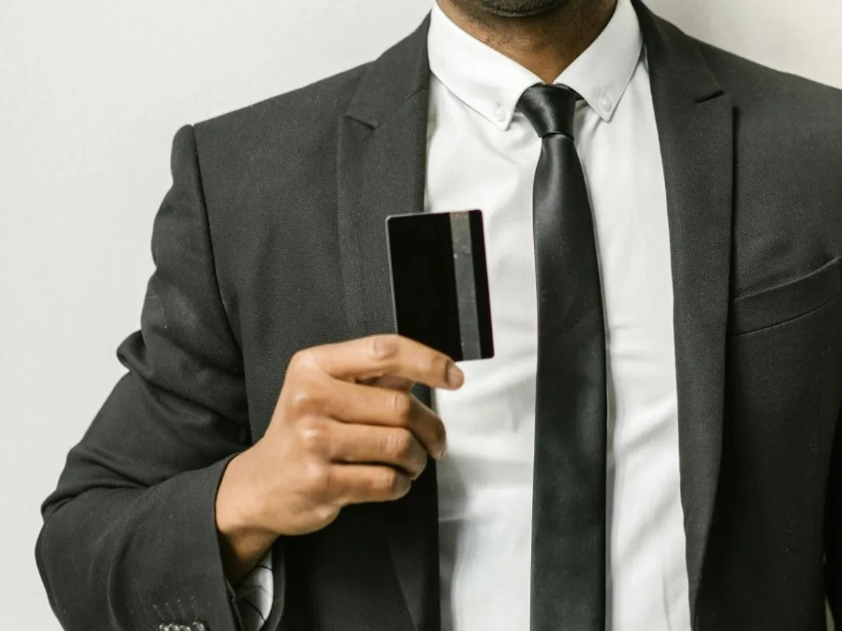 Bărbat în costum arătându-şi cardul de credit - Foto: Pexels/RDNE Stock project