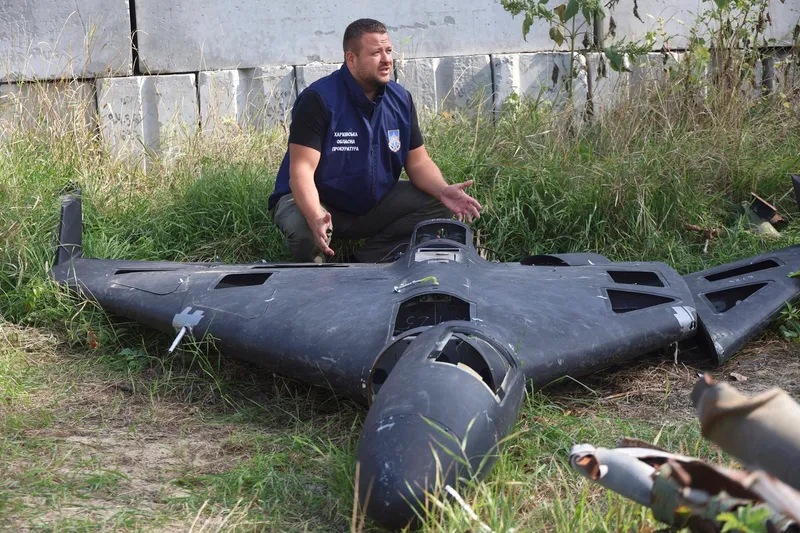 Un angajat al Procuraturii Regionale Harkov din Ucraina stă în genunchi lângă un fragment al unui drone Shahed găsit la locul unui atac rus în Harkov, Ucraina, pe 19 septembrie 2025 - Foto: Profimedia Images