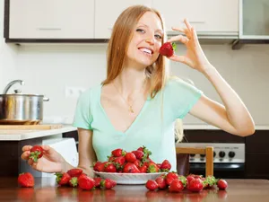 Femeie frumoasă care a așezat pe masă un bol cu căpșuni - Foto: Freepik