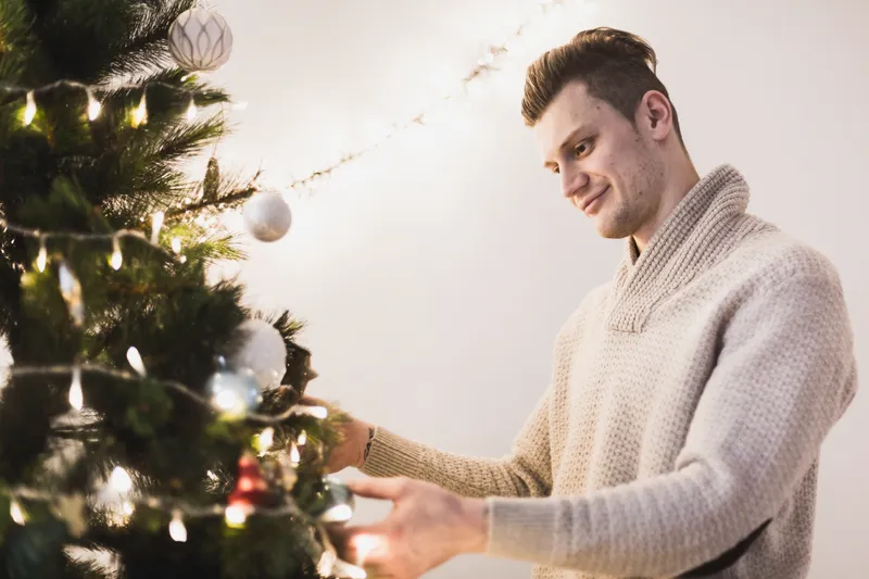 Bărbat care pun globuri în brad - Foto: Freepik (Imagine cu rol ilustrativ)