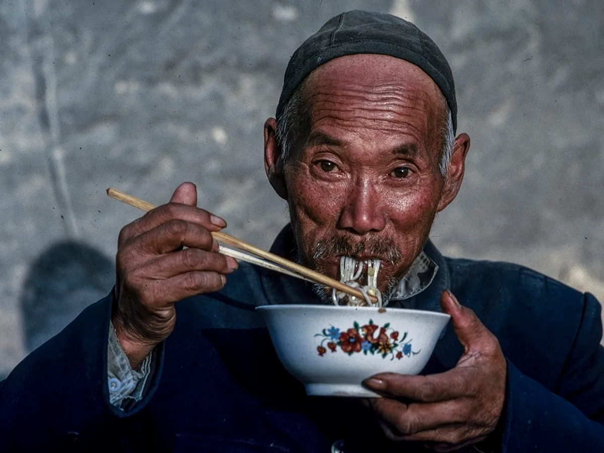 Chinez în vârstă mâncând cu ajutorul bețișoarelor - Foto: Profimedia