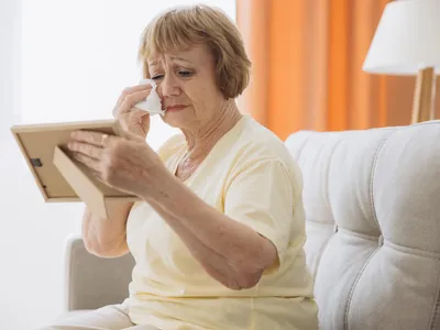Pensionară la pensie se uită la poze din tinerețe - Foto: Freepik