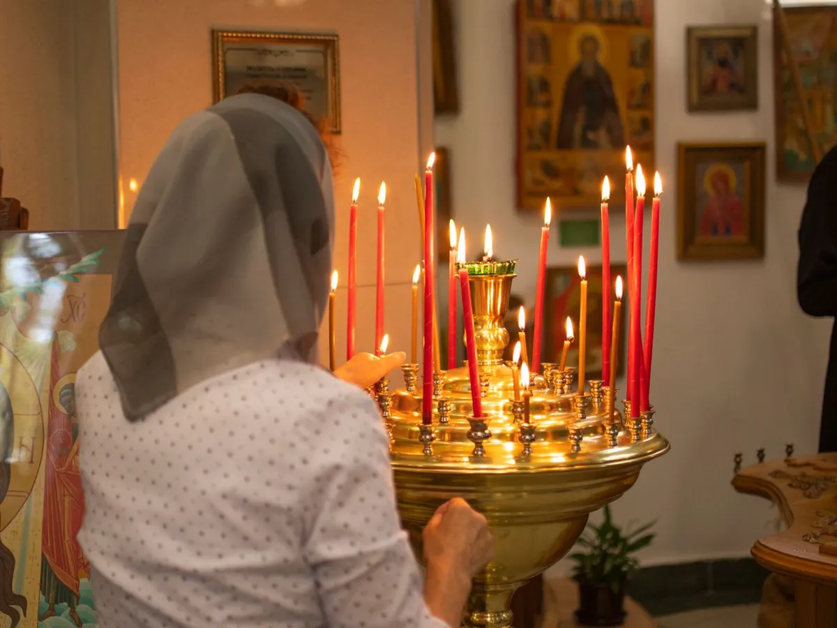 Femeie la biserică care aprinde lumânări - Foto: Magnific.com (Imagine cu rol ilustrativ)