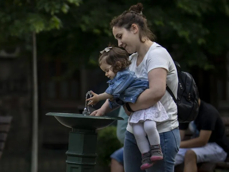 Femeie cu copil lângă o ţâşnitoare, în Bucureşti - Foto: Profimedia Images