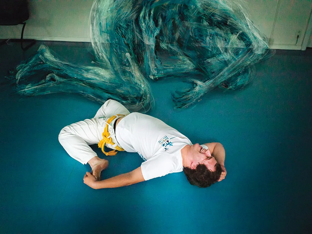Din nou în sala de antrenament la Capoeira. Acum e mult mai puternic. Își domină migrenele. Și poate să zâmbească