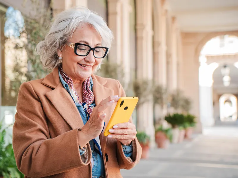 Pensionară verificând pe telefon dacă i-a intrat pensia - Foto: Freepik