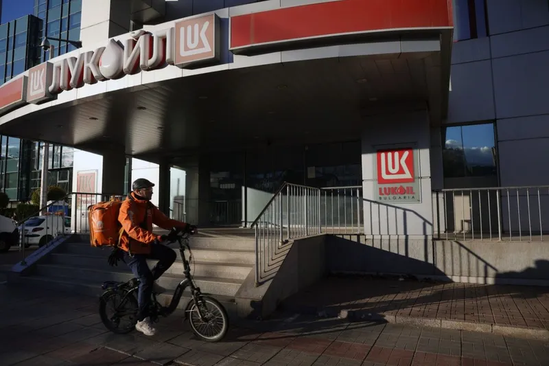 Un curier pedalează prin faţa sediului central al Lukoil din Sofia - Foto: Profimedia Images