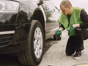 Bărbat care inspectează roțile unei mașini - Foto: Freepik