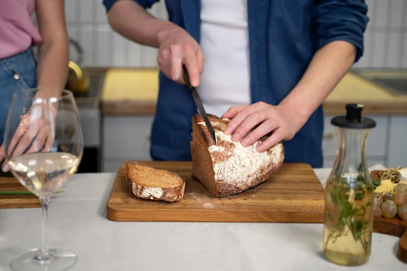 Persoană care taie o p&acirc;ine - Foto: Freepik (Imagine cu rol ilustrativ)