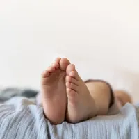 Plan apropiat cu picioare de bebeluş stând întins în pătuţul lui - Foto: Freepik/CC0