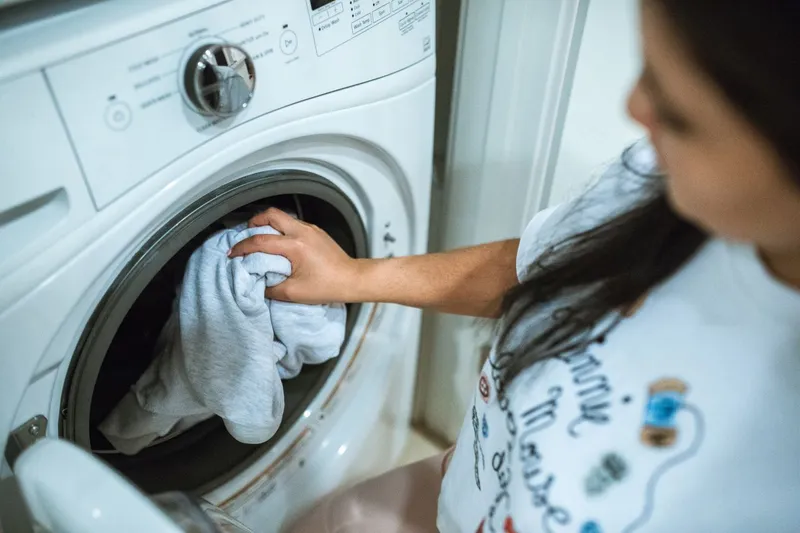 Femeie care pornește mașina de spălat rufe - Foto: Pexels (Imagine cu rol ilustrativ)