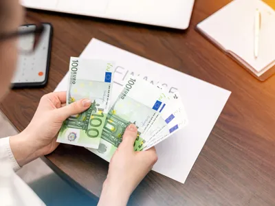 Femeie care lucrează cu finanțe numărând bani pe masă - Foto: Magnific.com (Imagine cu rol ilustrativ)