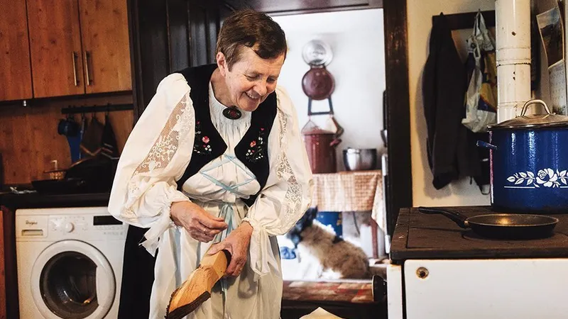 Româncă de origine germană punând lemne pe foc în satul Viscri
