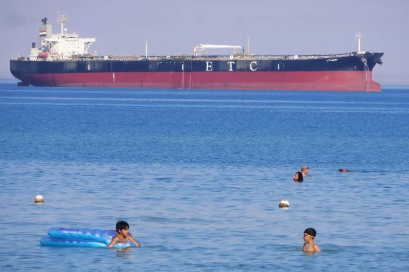 Egiptenii aflaţi &icirc;n vacanţă &icirc;noată &icirc;n apele Golfului Suez, l&acirc;ngă petrolierul ETC Ramsis - Foto: Profimedia Images