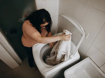 O femeie adultă pune haine într-o mașină de spălat  - Foto: Pexels (Imagine cu rol ilustrativ)