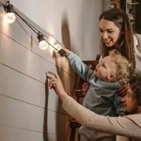 Tânără familie cu copil admirând aranjamentele cu lumini, în afar casei - Foto: Pexels/Pavel Danilyuk