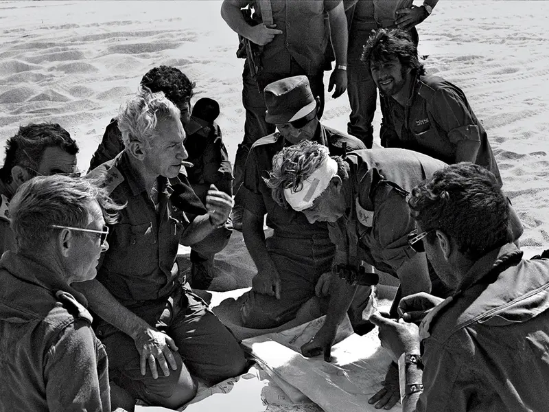 LA COMANDAMENT În sens invers acelor de ceasornic, de la centru: Ariel Sharon (cu capul bandajat) cu Moshe Dayan și șeful Statului Major al Armatei, Chaim Bar-Lev, în Sinai