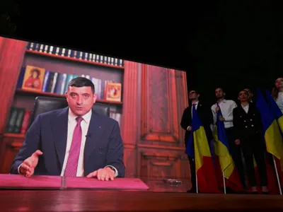 George Simion, pe un ecran gigant, transmiţând mesajul său video, după rezultatele exit-poll-ului - Foto: Profimedia Images