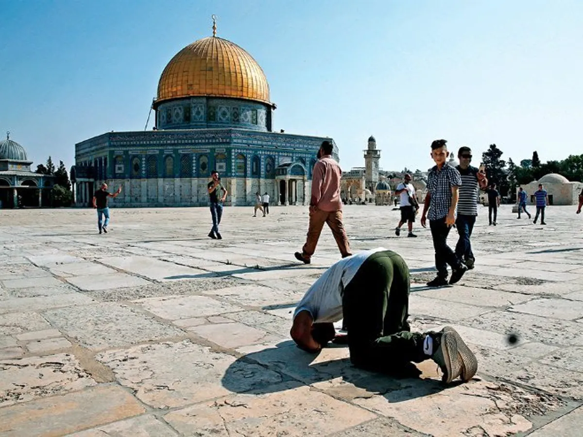 Un musulman efectuează sujud, lângă Cupola Stâncii (Muntele Templului) din Ierusalim