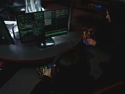 Doi tineri folosind computere, în clarobscur - Foto: Pexels/Tima Miroshnichenko