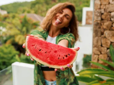Femeie frumoasă care ține în mână o felie de pepene verde - Foto: Freepik