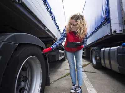 Şoferiţă de camion verificându-şi cauciucurile, înainte de cursă - Foto: Magnific.com/aleksandarlittlewolf