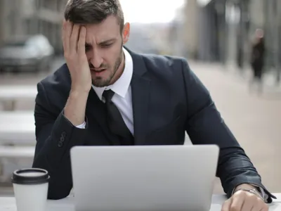 Bărbat supărat, aflat în stradă, uitându-.se pe laptop - Foto: Pexels/Andrea Piacquadio