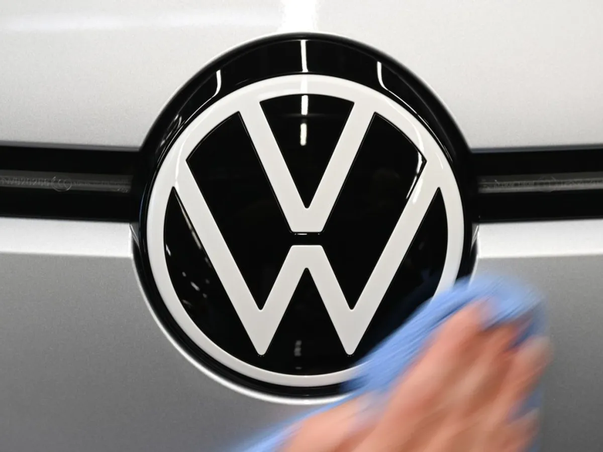 Un angajat lustruieşte logo-ul VW, de pe o maşină aflată pe linia de asamblare de la uzina din Zwickau, Saxonia - Foto: Profimedia Images