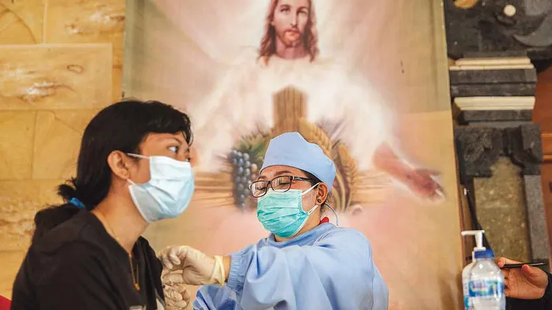 ȘTIINȚĂ ȘI CREDINȚĂ Un doctor
administrează o doză de vaccin AstraZeneca la Biserica Catolică a Duhului Sfânt din Parohia Babakan din zona Canggu din Bali, Indonezia - Foto: Getty Images