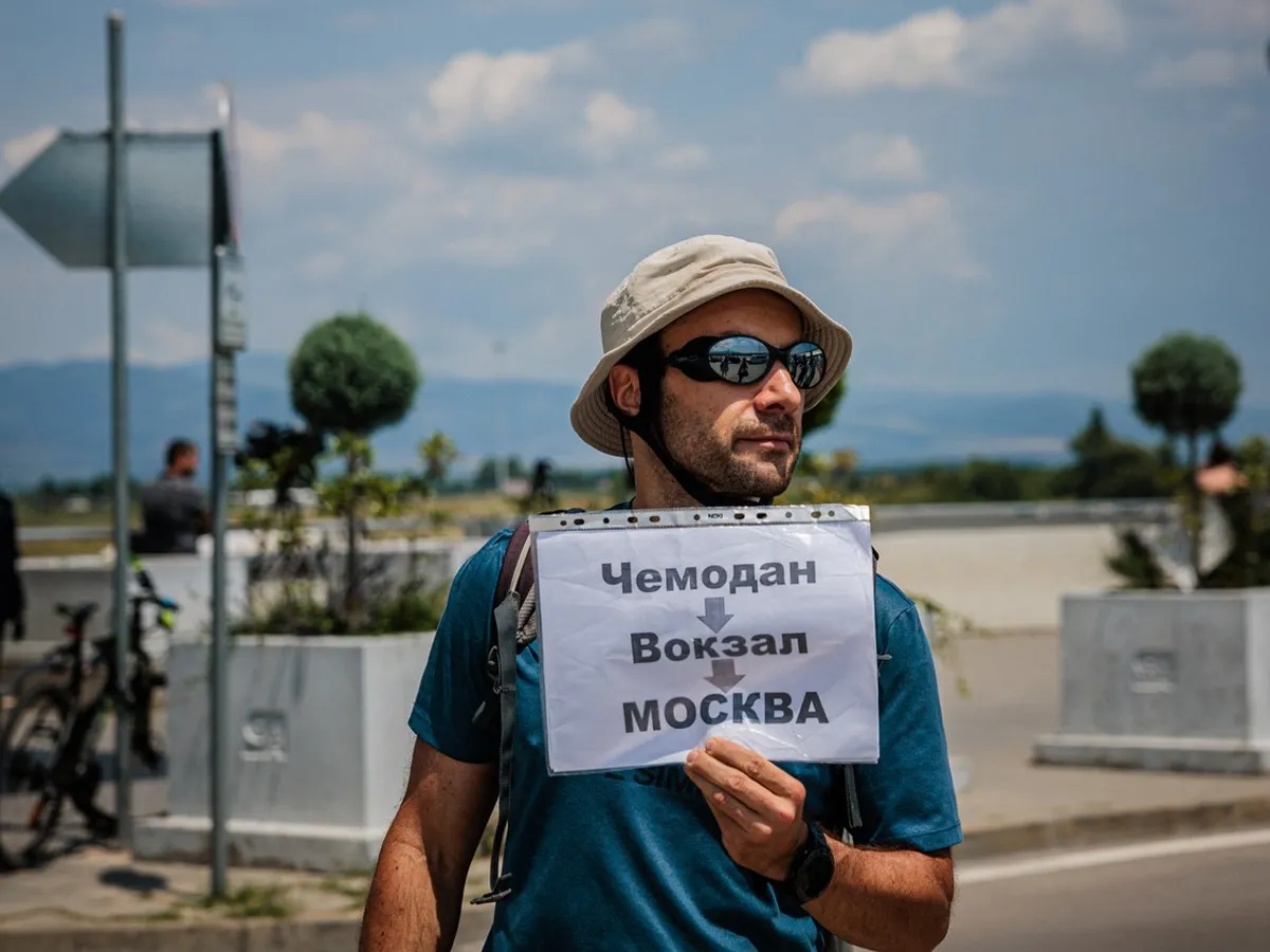 Un protestatar bulgar ține o pancartă, în timp ce personalul misiunii diplomatice a Rusiei și familiile lor sosesc îpe aeroportul din Sofia - Foto: Profimedia Images