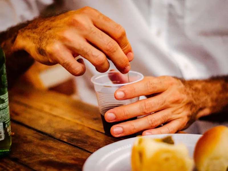 Bărbat preparându-şi ceaiul într-un pahar de plastic. Dejunul îl aşteaptă, într-o farfurie de plastic - Foto: Pexels/ray guesc