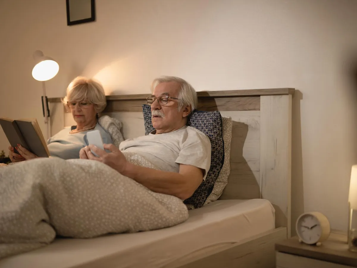 Cuplu matur relaxându-se în pat seara - Foto: Magnific.com (Imagine cu rol ilustrativ)