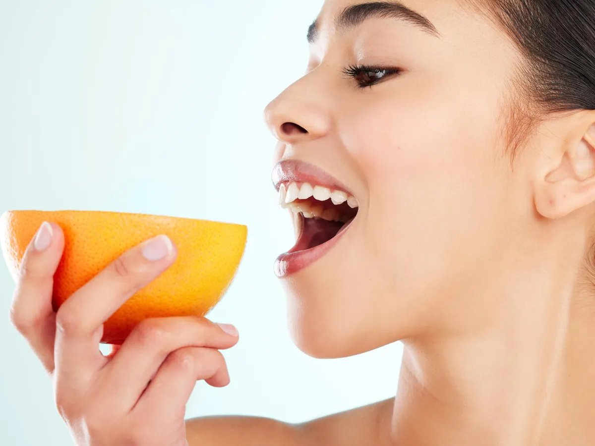 Femeie care mănâncă o portocală - Foto: Freepik (Imagine cu rol ilustrativ)